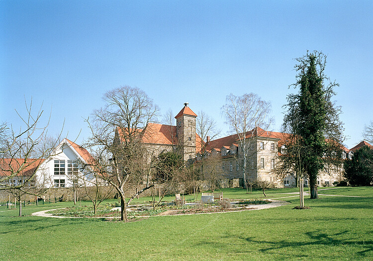 Klostergarten mit Rundweg, Sträuchern und Bäumen.